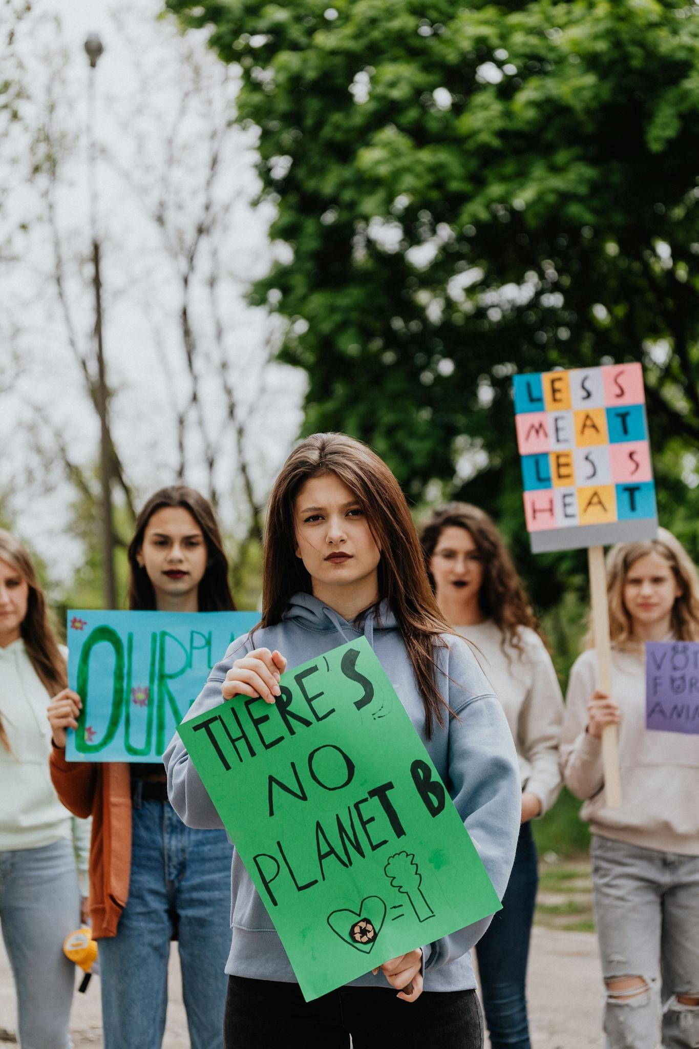 Young women protesting for environmental change, holding vibrant signs outdoors.